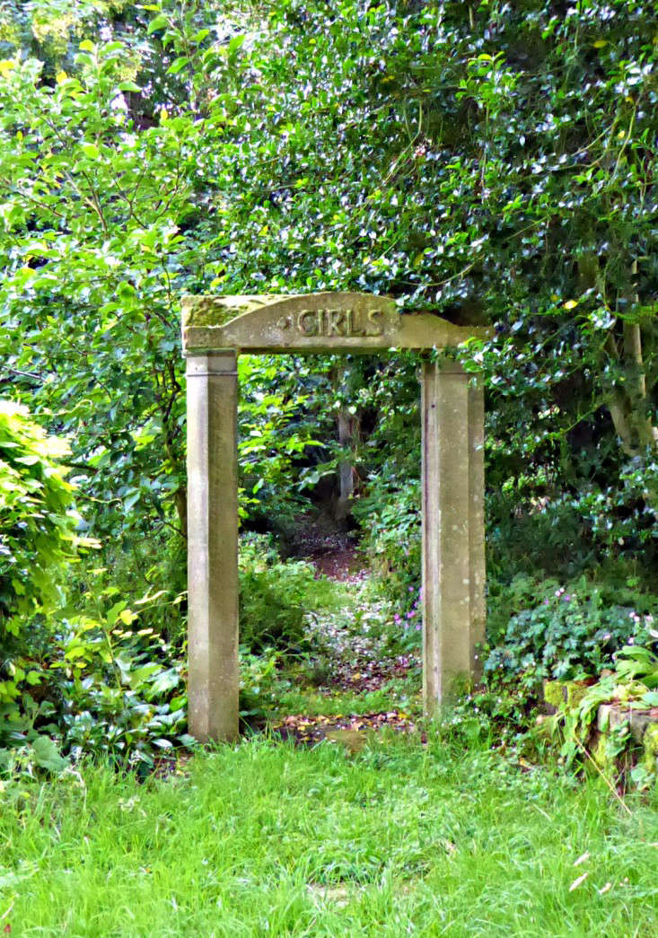 Throughout the garden are whimsical details including a salvaged stone arch from an old school repurposed to frame the entrance into a shady walk.