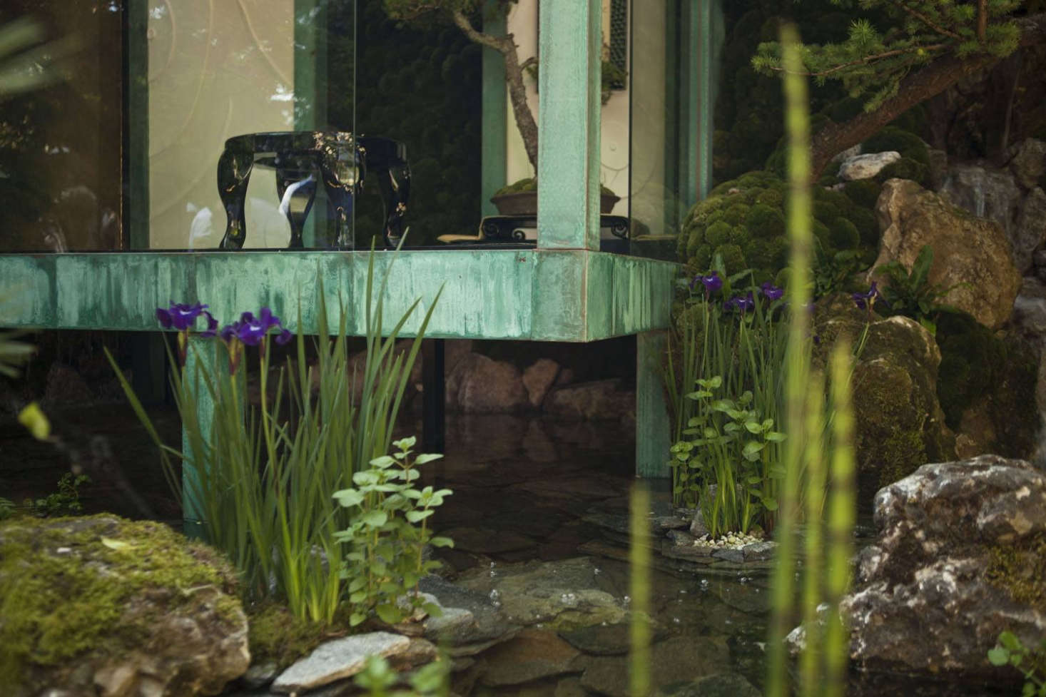 Moat alternative: water flowing under and around the structure that is clad in aged copper.