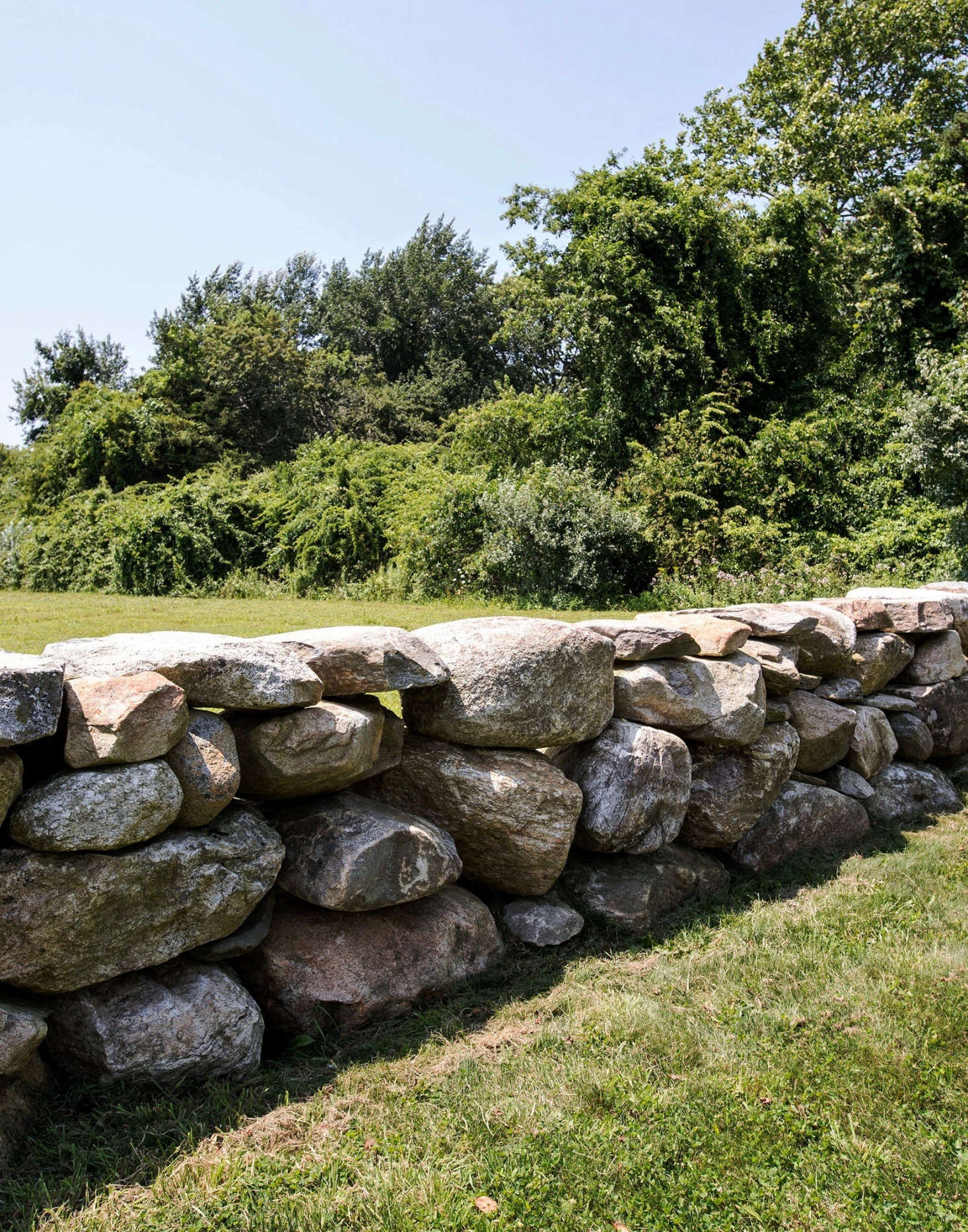 A low, stacked stone wall creates a sense of enclosure around the main house.