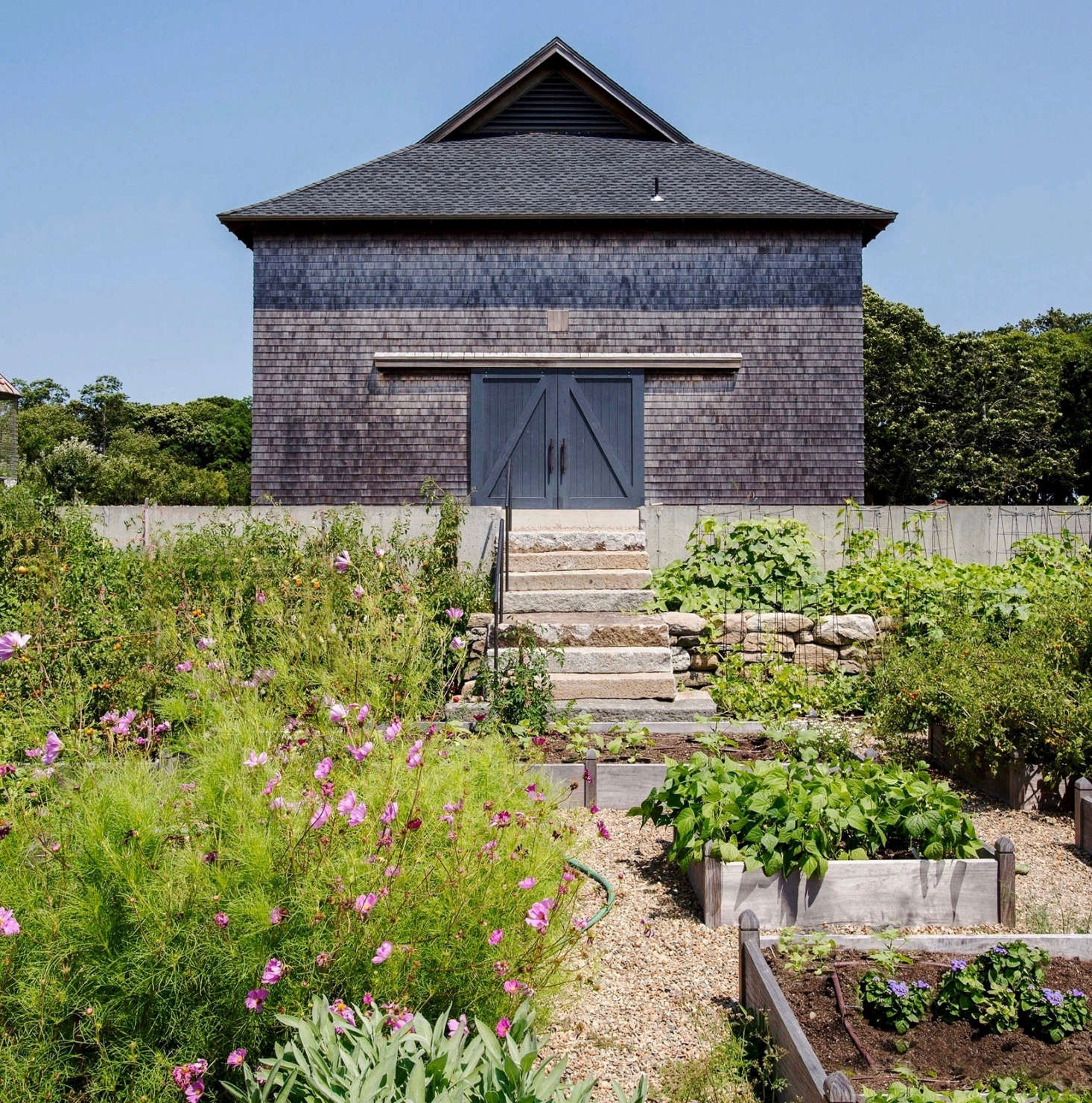 Near the main barn, the Glasgows grow food and flowers in a raised-bed garden. Seasonal produce, including the tomatoes and peppers shown here, is for sale at a farm stand (where customers leave money in an honor box).