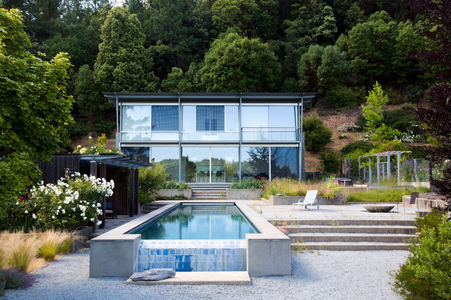 A glass box, the house overlooks the swimming pool and was sited to take advantage of sweeping ridge views. Off to the right, you can see the garden