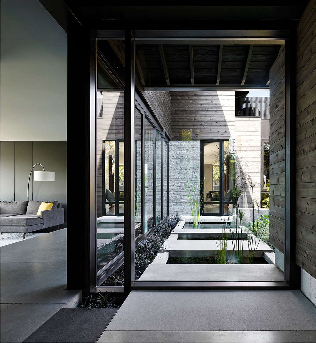 The courtyard garden, newly visible from the front door. In the house’s initial design, a solid wood front door opened onto a large coat closet, which walled off the courtyard on one side. The design team replaced the closet with floor-to-ceiling glass windows, so the courtyard garden is the first thing visible upon entering the house.