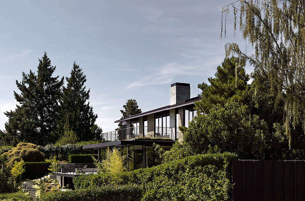 The back of the house looks toward Seattle’s Lake Washington. Though the house’s footprint remained unchanged, the architects flattened a formerly vaulted dining room ceiling to allow for a new, top-floor deck off the master bedroom. From a lower deck located off the kitchen, poured concrete stairs wind down to another patio and lawn.