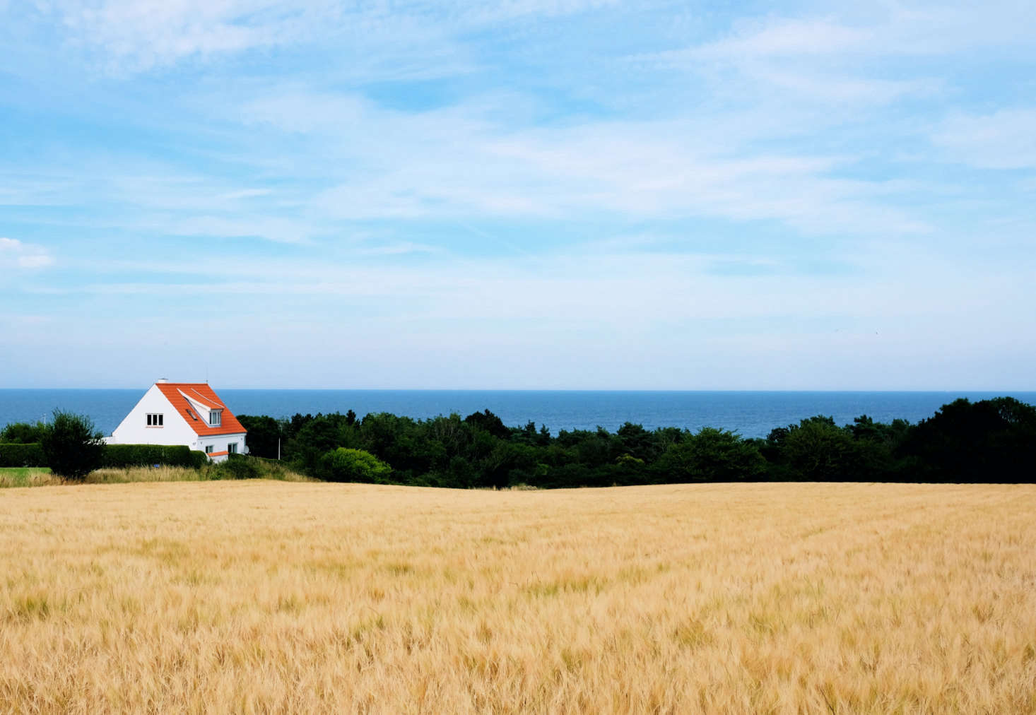 A red roof adds color to a landscape in Tejn on the northeastern coast of the island of Bornholm. Photograph by Lars Plougmann via Flickr.