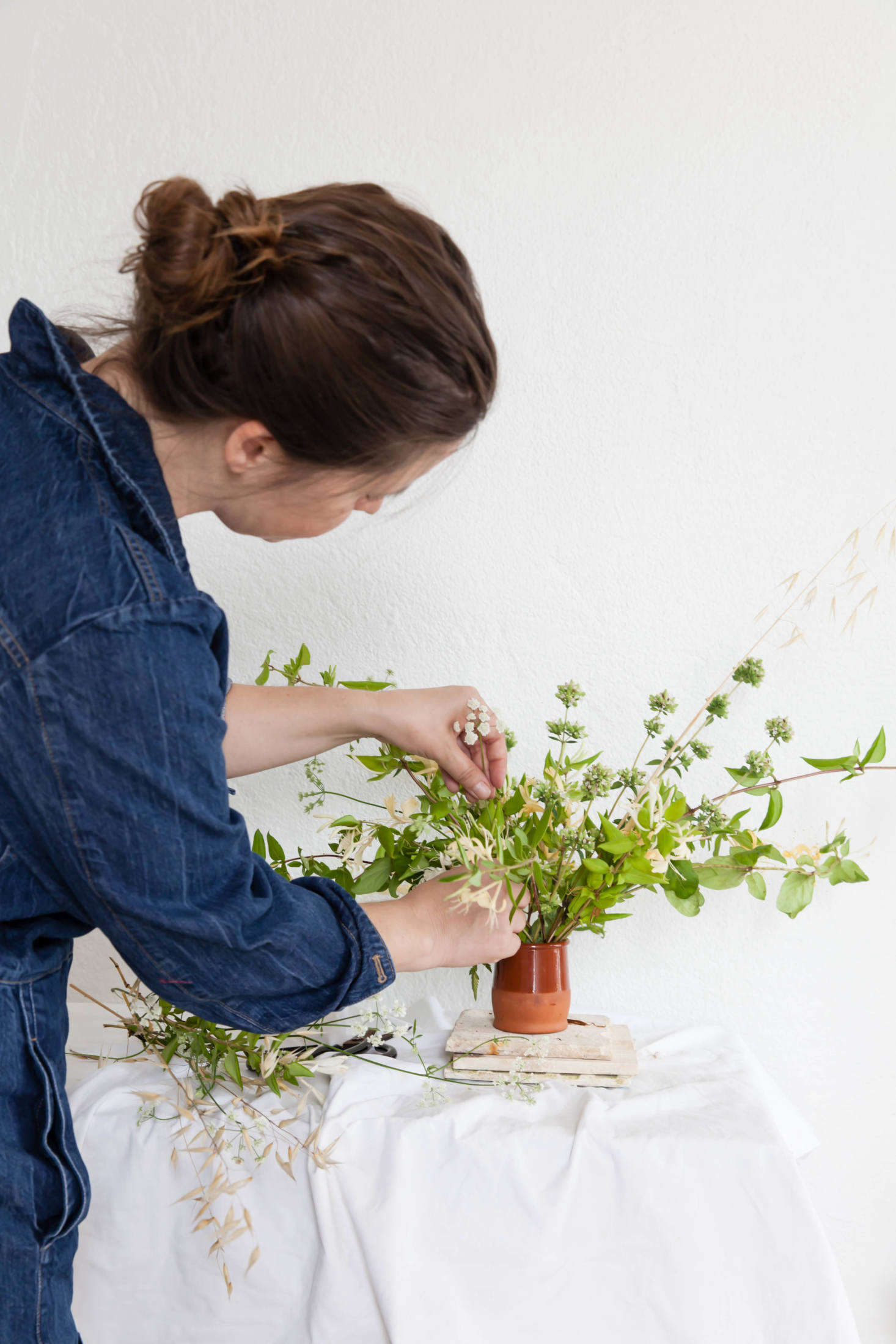 A fragrant meadow arrangement of honeysuckle, dried grasses, wild flowering oregano, and cow parsley adds a bit of green to a whitewashed room.