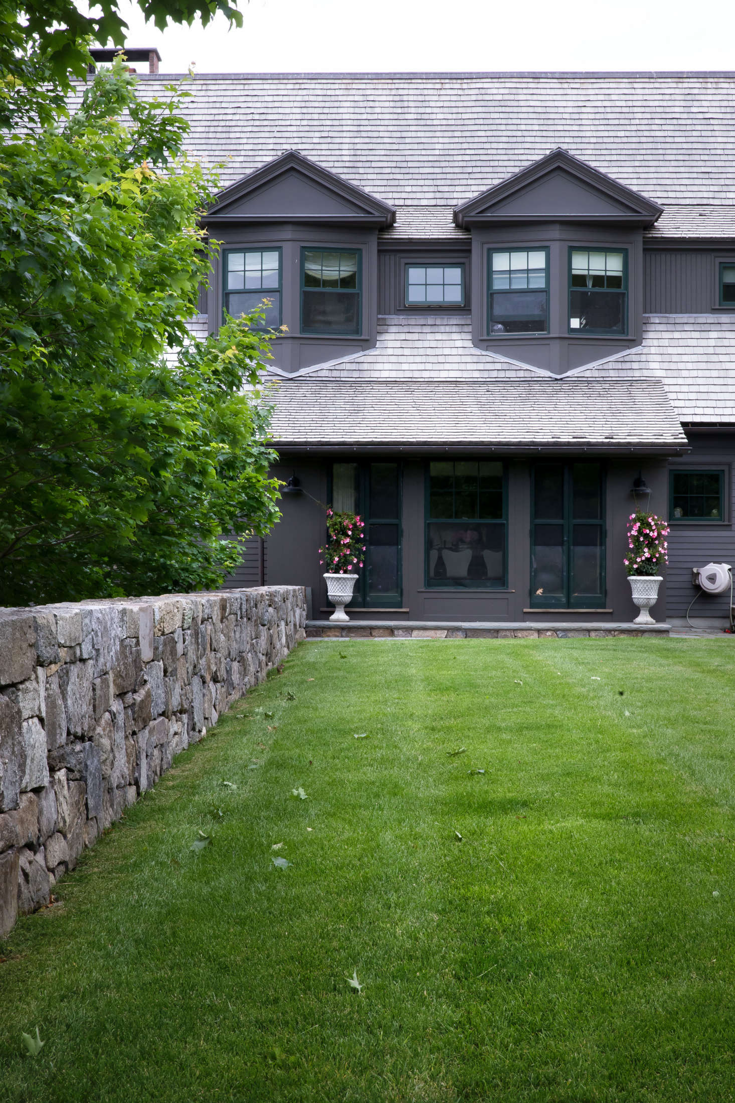 In front of the shingle-style house built by Albert, Righter & Tittman Architects, a line of sugar maple trees and another newly built fieldstone wall shelter a generous lawn, the main outdoor living and recreation space.