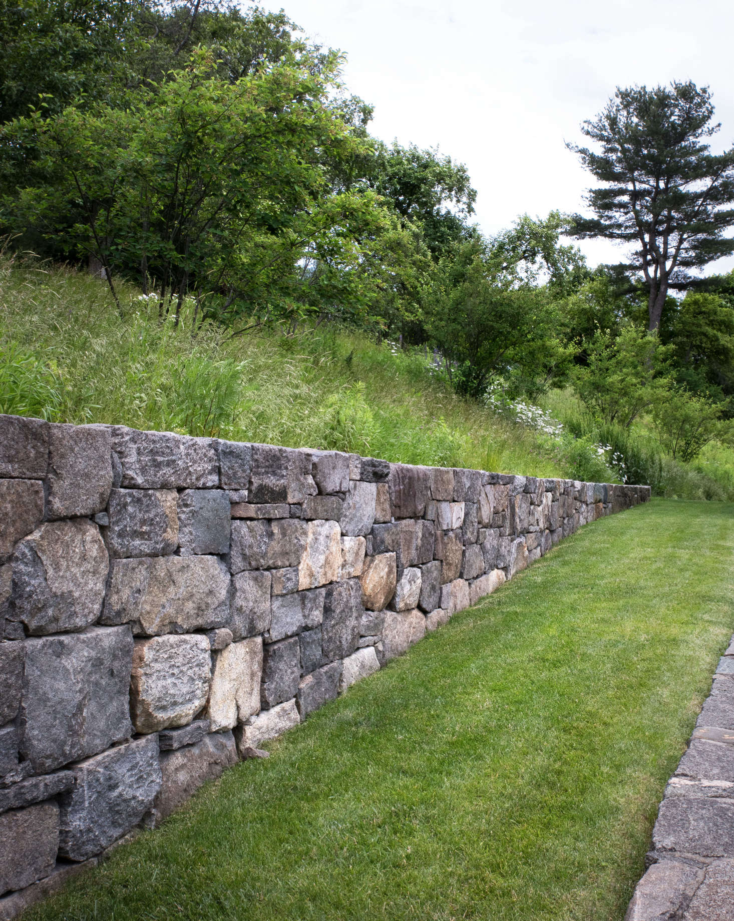 The four, new, fieldstone walls on the property were constructed using locally sourced stones carefully chosen for its character and appearance. All new walls utilized stones that were intentionally larger and rough-hewn to blend with the rustic surroundings. Some show a combination of “faces,” some are naturally weathered, while others show a tooled edge; all so that the newly built wall feels older.