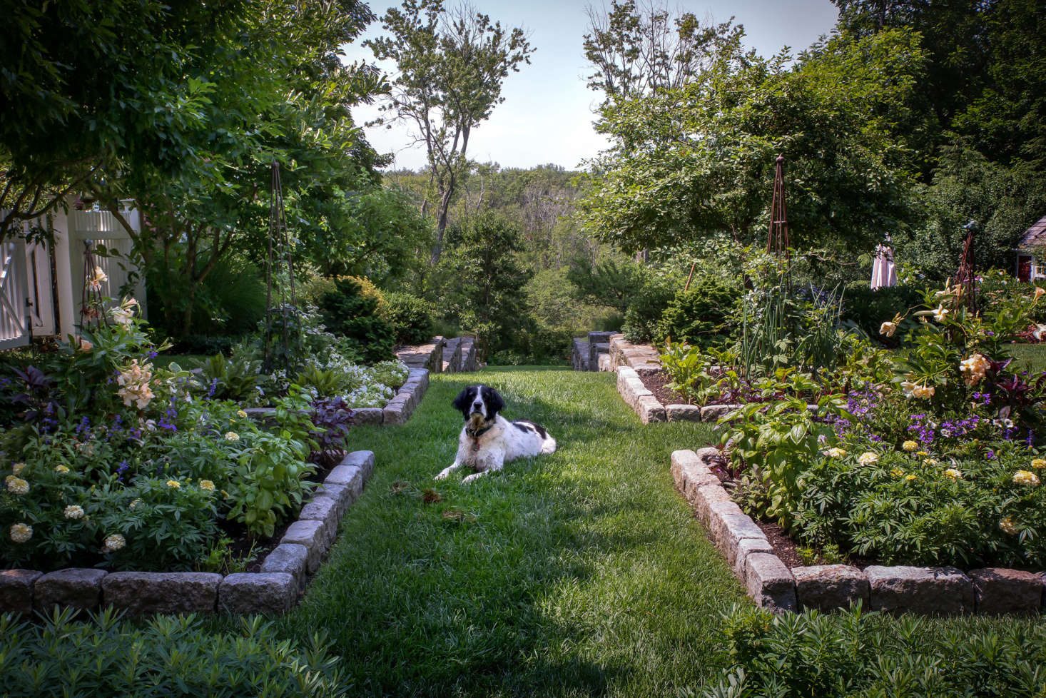 Creating a path that leads past the pool to the lower-level vegetable gardens, four garden beds edged with cobble stones host herbs and flowers.