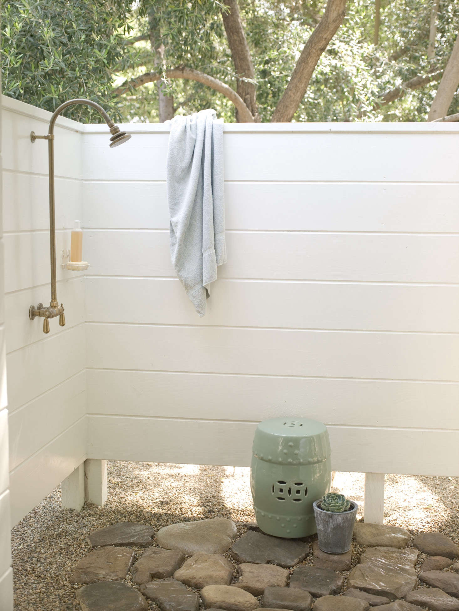 An outdoor shower off of the studio has a stone floor and a privacy enclosure, for rinsing off in the garden.